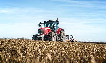 Tractor agricultural machine cultivating field.